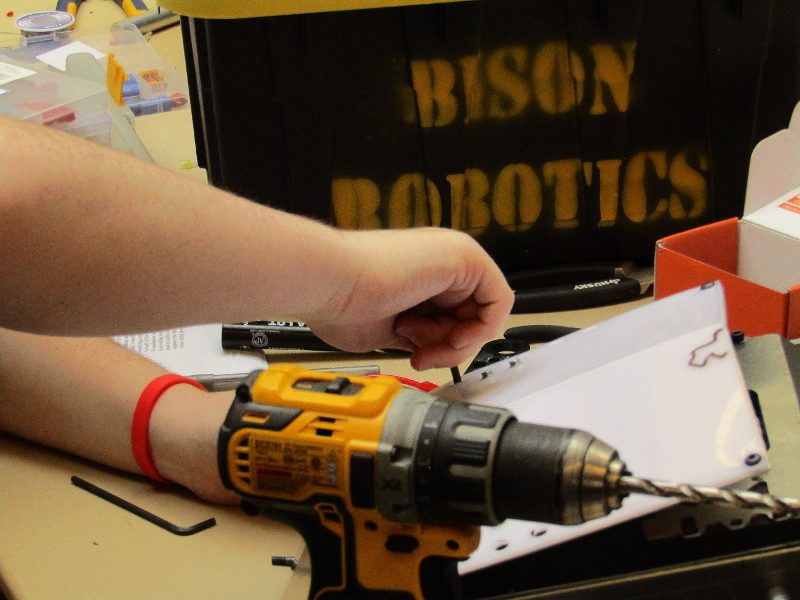 Drilling a white polymer plate in the Bison Robotics shop.