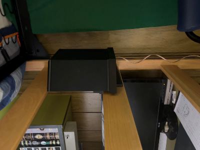 A bookshelf speaker on the printed bracket, hooked to a wooden bed frame.